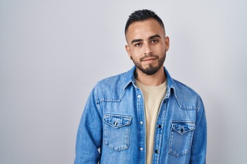 Young hispanic man standing over isolated background looking sleepy and tired, exhausted for fatigue and hangover, lazy eyes in the morning.