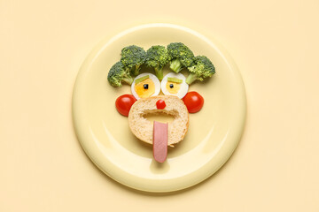 Plate with funny children's breakfast in shape of face on beige background