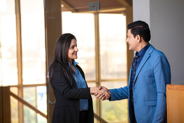 Young indian businesswoman shake hand with businessman at office.