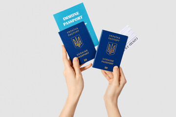 Woman with Ukrainian and immune passports on light background