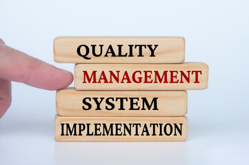 Quality Management System Implementation text on wooden blocks. Business culture and Operational excellence concept