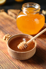 Fototapeta premium Golden honey in wooden bowl with dipper and jar on rustic wood board, natural sweetener and healthy food