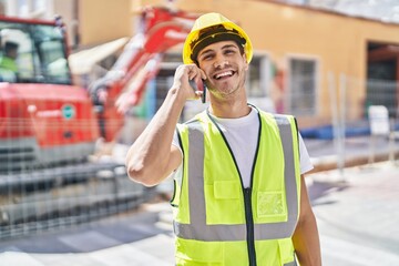 Young hispanic man architect smiling confident talking on smartphone at park