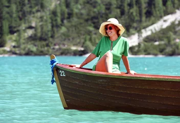 Foto op Canvas girl with cap smiling while on vacation on top of a boat in a mountain lake © fabrus