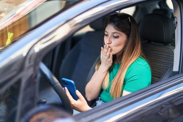 Fototapeta na wymiar Young hispanic woman having video call sitting on car at street