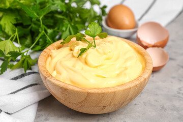 Bowl with tasty mayonnaise sauce on grunge background, closeup
