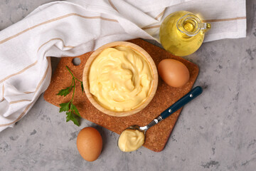 Bowl with tasty mayonnaise sauce and ingredients on grunge background