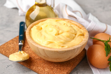 Bowl with tasty mayonnaise sauce on grunge background, closeup