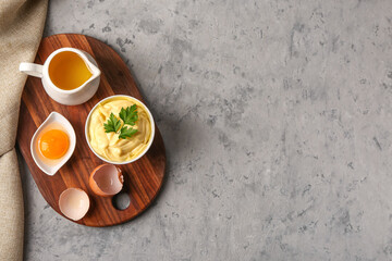Bowl with tasty mayonnaise sauce and ingredients on grunge background