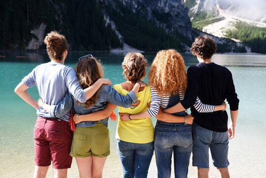 Group of friends of different nationalities on vacation on a mountain lake in the middle of nature, take pictures and celebrate spring or summer
