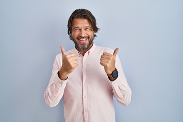 Handsome middle age man wearing elegant shirt background success sign doing positive gesture with hand, thumbs up smiling and happy. cheerful expression and winner gesture.