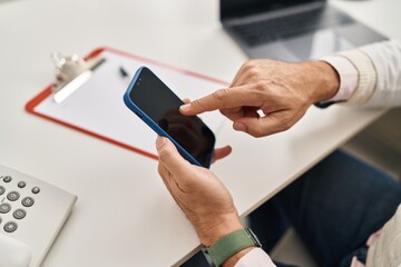 Middle age man doctor using smartphone working at clinic