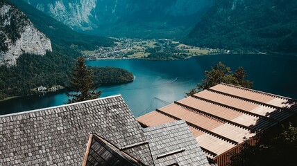 Drone shot of roofs of houses on the coast of a small lake surrounded by hills in Hallstatt, Austria