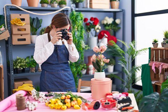 Young woman florist make photo by proffesional camera to flowes at florist shop