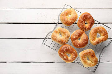 Grid of tasty bagels with sesame seeds on light wooden background