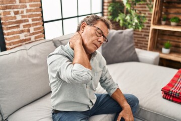 Middle age man touching neck suffering for pain at home