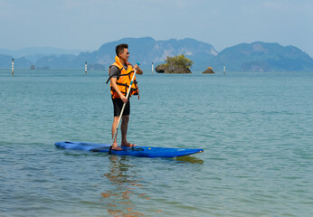 Asian man Playing SUP Board in Blue Sea in Summer Vacation