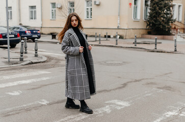 Naklejka premium A woman crossing the street in a coat and jeans