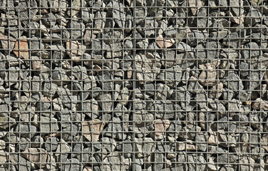 Gabion, texture, background. Fragment of gabion net, wall design. New technologies in the manufacture of retaining walls and fences. Landscaping. Fencing decorative elements. Gabion in sunlight