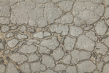 Textured backdrop. Mosaic texture, background of an old, cracked road. An old asphalt surface, background. Detailed texture of the bitumen close-up. Screen short. Road foundation