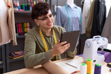 Non binary man tailor smiling confident using touchpad at atelier