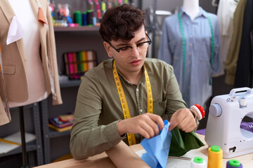Non binary man tailor holding cloths at atelier