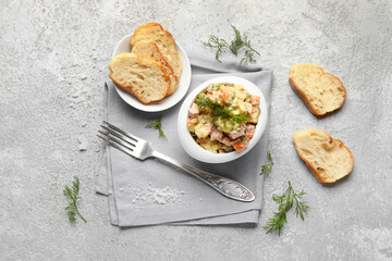Bowl of tasty Olivier salad on light background