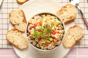 Plate of tasty Olivier salad on pink tile background