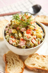 Bowl of tasty Olivier salad on table