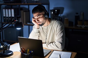 Obraz premium Young handsome man working using computer laptop at night thinking looking tired and bored with depression problems with crossed arms.