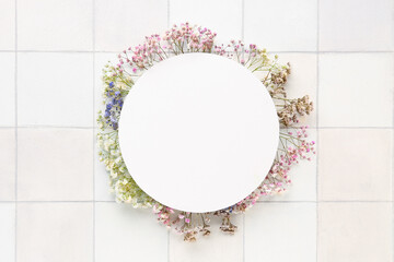 Blank card with gypsophila flowers on white tile background