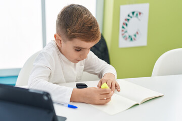 Adorable hispanic boy student using touchpad underlining on notebook at classroom