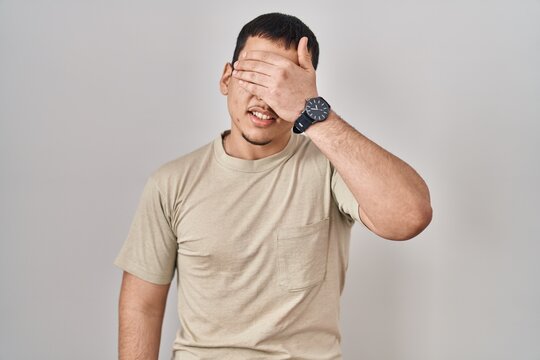 Young arab man wearing casual t shirt smiling and laughing with hand on face covering eyes for surprise. blind concept.