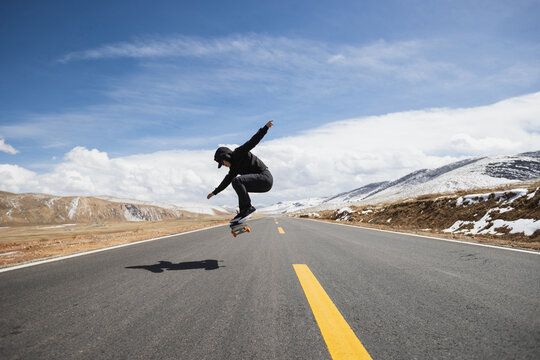Asian woman skateboarder skateboarding on snowy country road