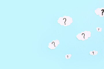 Paper clouds with question marks on blue background