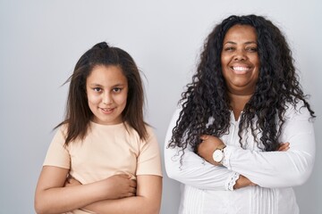 Mother and young daughter standing over white background happy face smiling with crossed arms looking at the camera. positive person.
