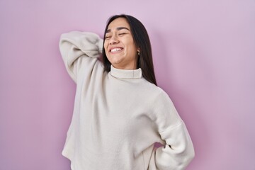 Young south asian woman standing over pink background stretching back, tired and relaxed, sleepy and yawning for early morning