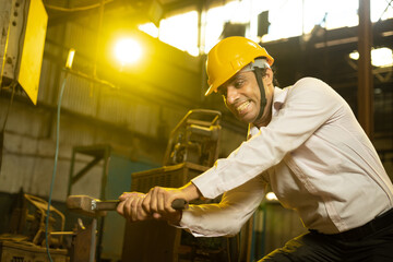 Indian worker wearing yellow hard hat or helmet working in industrial factory. hit hammer, Skill india.