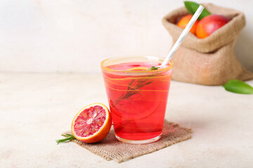Glass of tasty blood orange lemonade on light background
