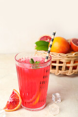 Glass of tasty blood orange lemonade on light background