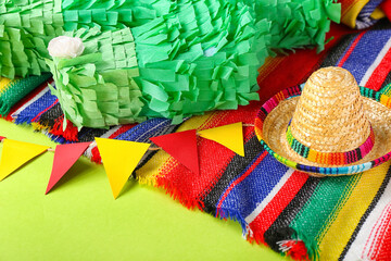 Fototapeta na wymiar Mexican pinata with sombrero hat, flags and serape on green background, closeup
