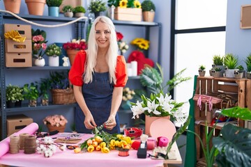 Young blonde woman florist make bouquet of flowers at florist store