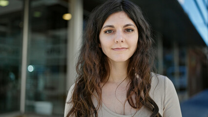 Young beautiful hispanic woman standing with serious expression at street