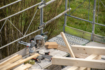 Circular saw from carpenter on a railing next to rafter of a new wooden roof