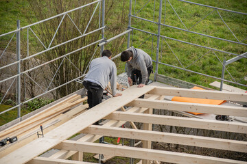 Two young carpenters building a carport. Apprentice learns from trainer.