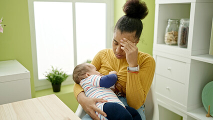 Mother and son sitting on table stressed breastfeeding baby at dinning room