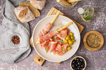 Plate of tasty Italian Grissini with jamon on grunge background