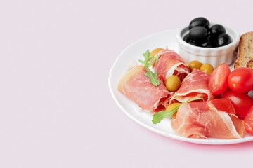 Plate with slices of tasty jamon on pink background, closeup