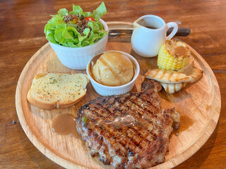 Pork steak and pototo on wood dish.