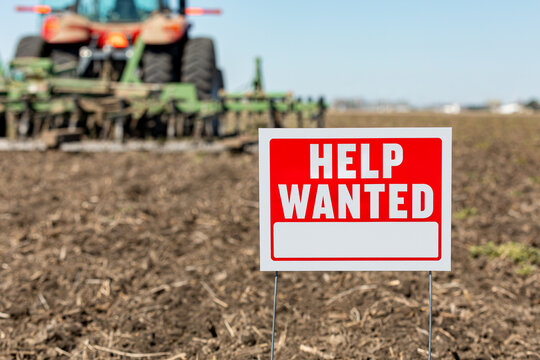 Help wanted sign in farm field during spring planting season. Farm labor shortage, agriculture job market and employment concept.